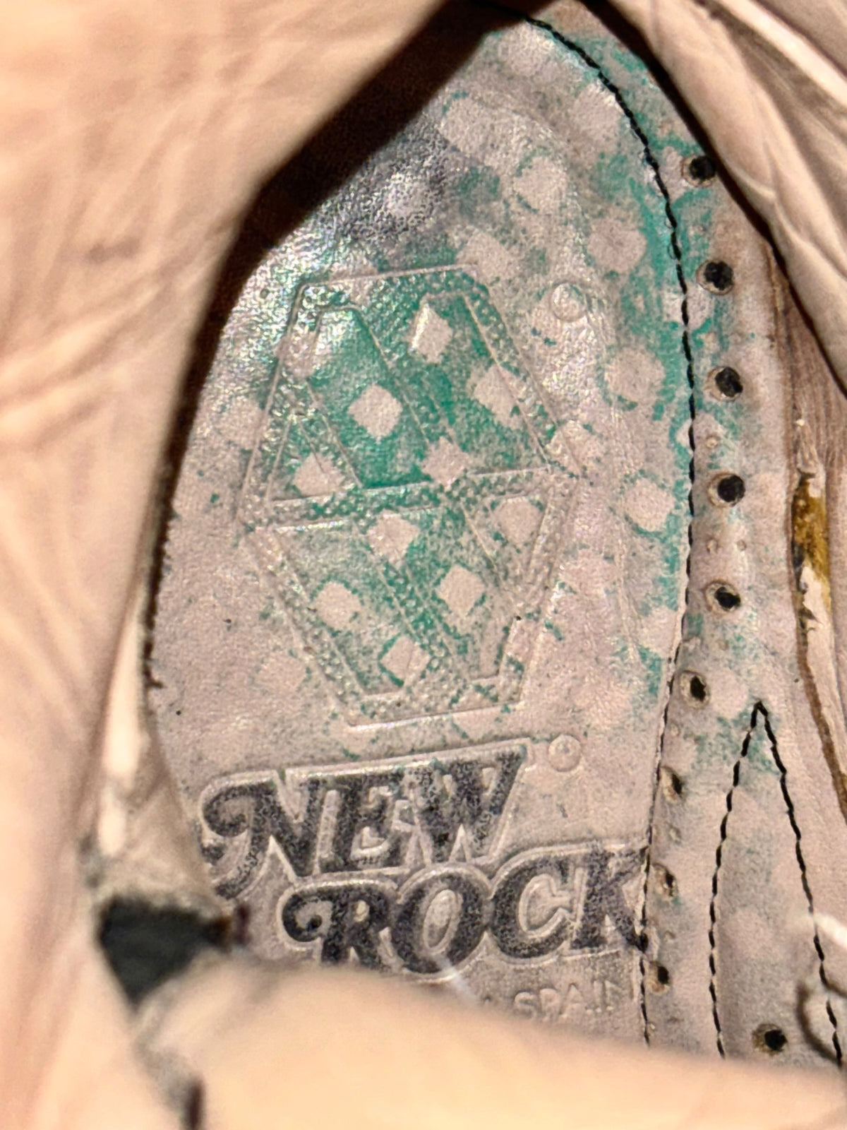 Knee-high boot interior label with “NEVER ROCK” text and stitched eyelets