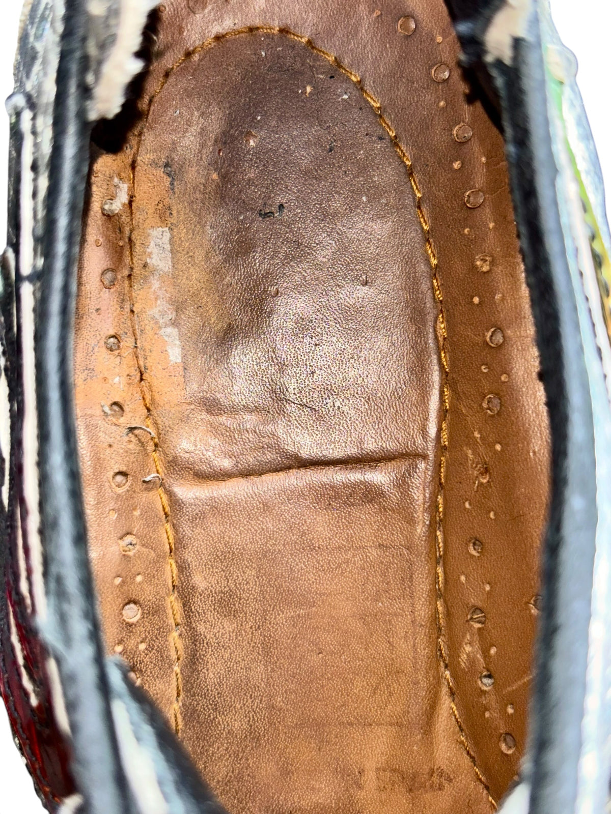 Brown boot insole with yellow stitch edging and metal eyelet detail
