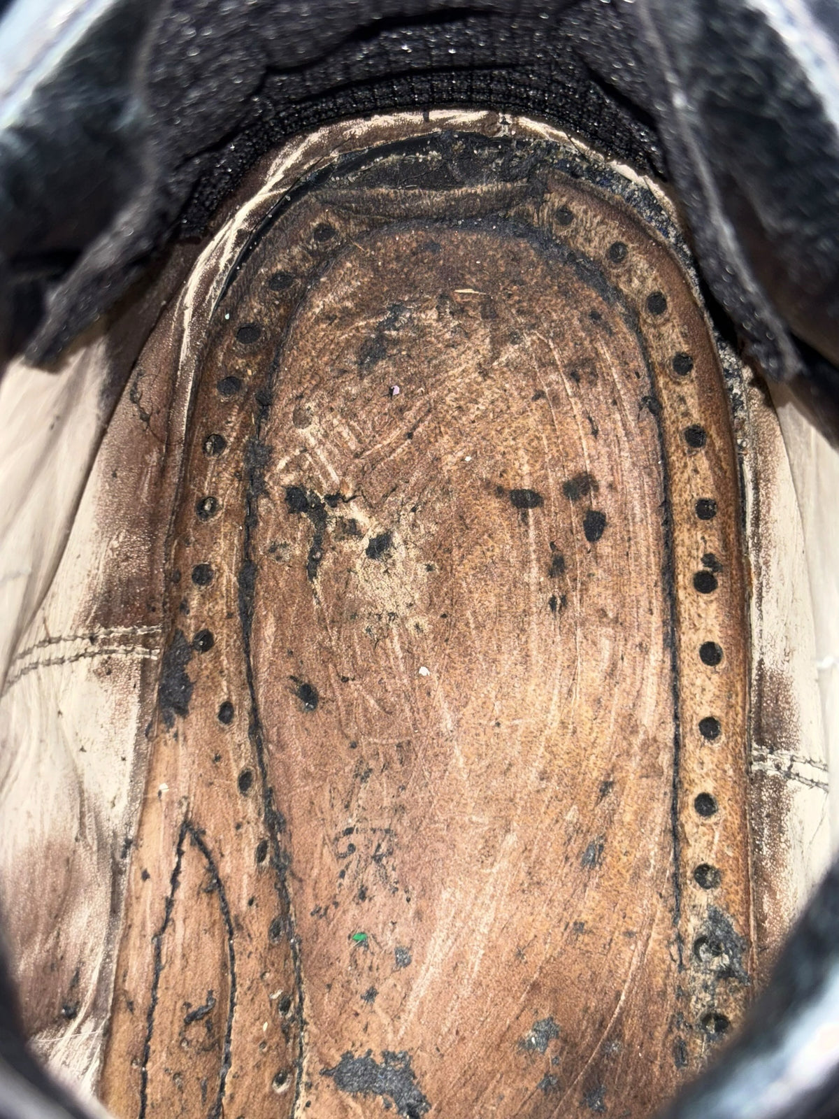 Close-up of worn boot interior leather with rivet-studded arch detail