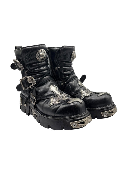 Black leather platform boots with chunky tread sole, straps, and decorative metal plates