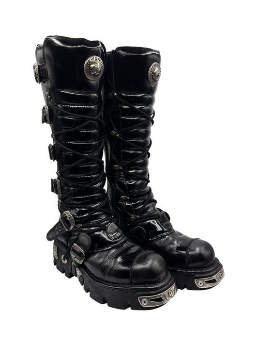 Black knee-high leather combat boots, side buckles and stacked sole with metal guards