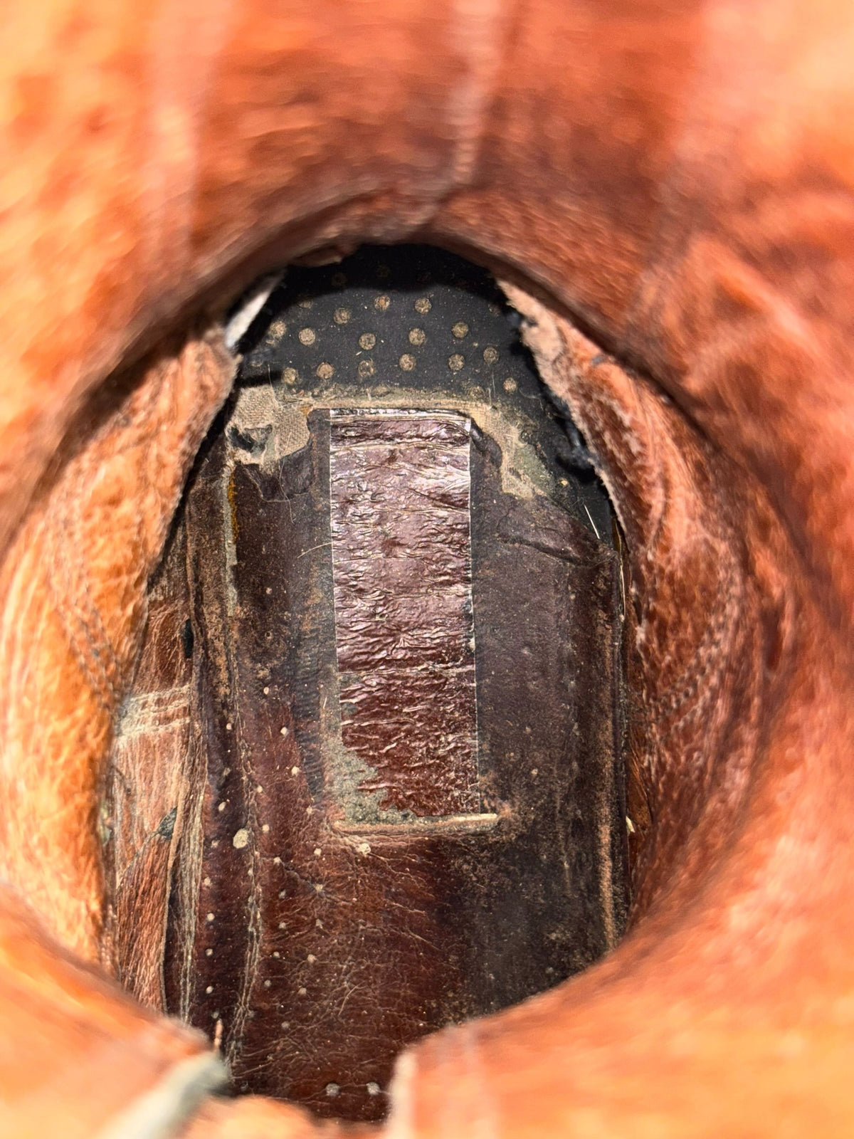 Mid-calf buckled boot interior with worn insole and rugged lining