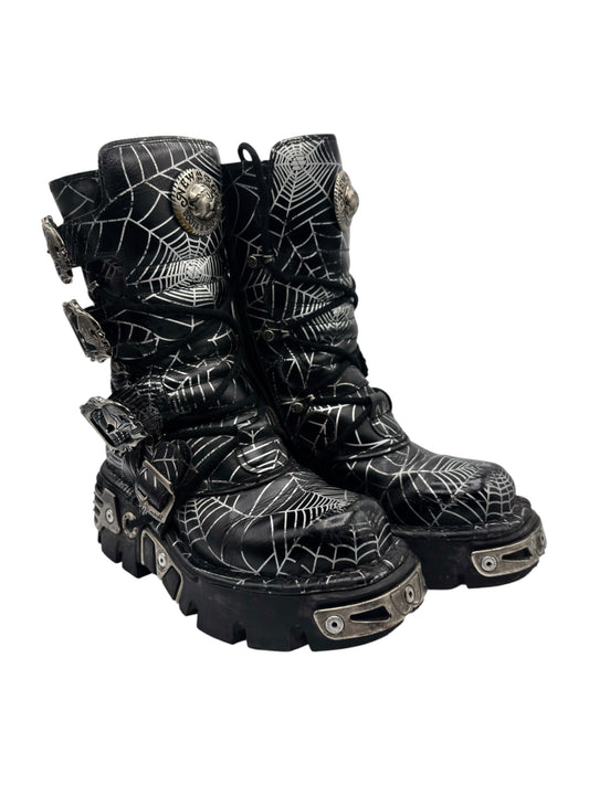 Three-quarter view of black cobweb boots with lace-up straps and lug sole