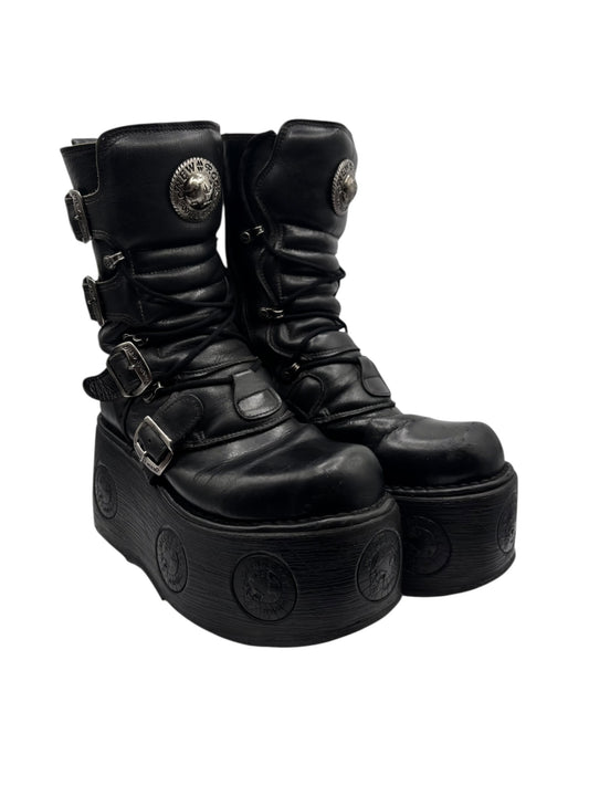 Black leather platform boots with side straps, buckle closures, and thick lug sole