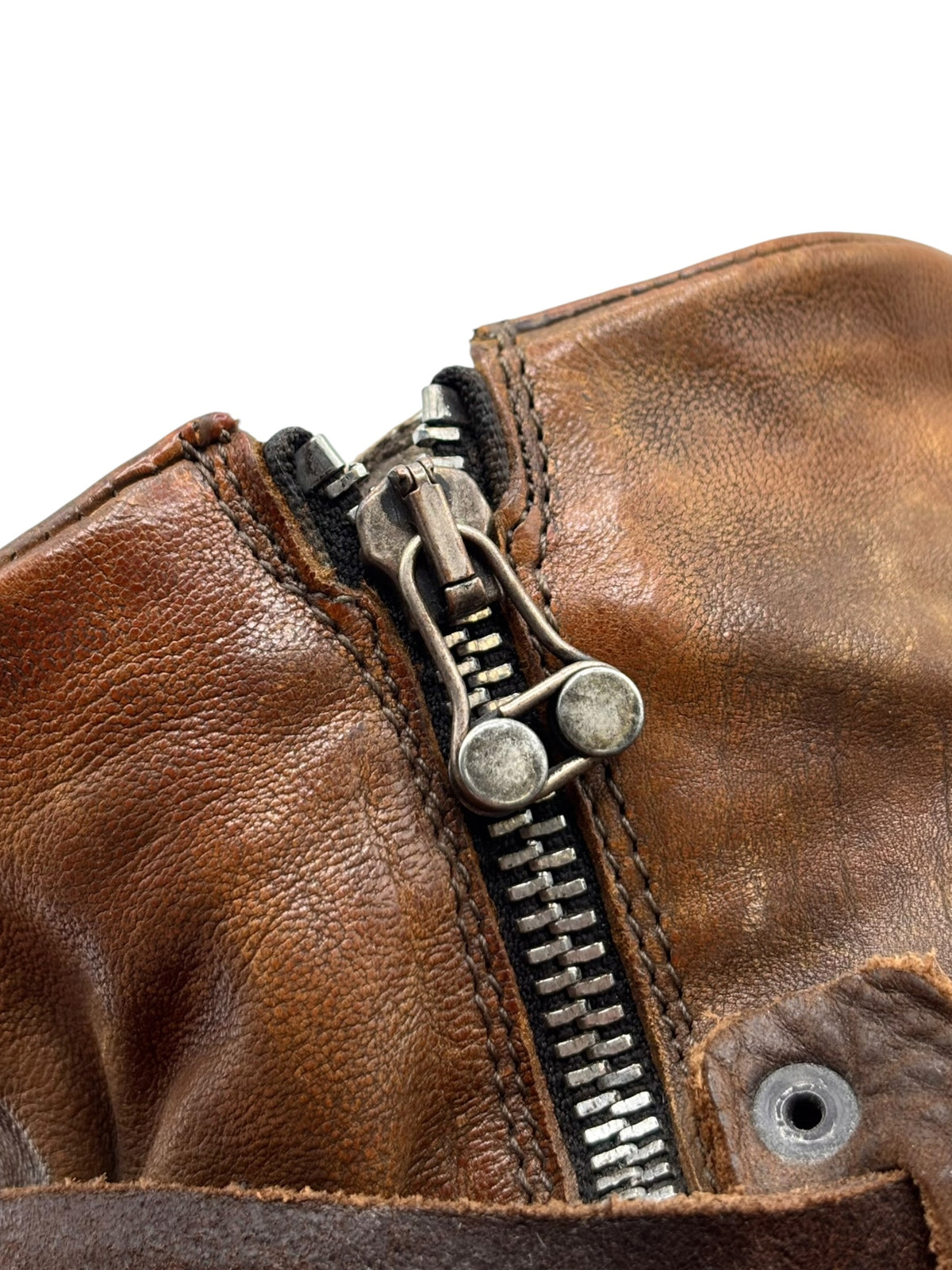 Brown leather ankle boot close-up of side zipper and metal pull tabs