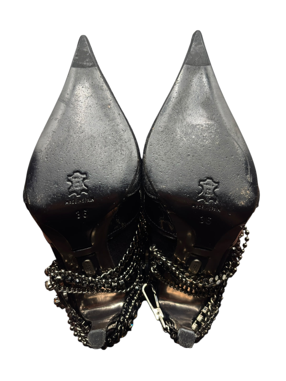 Pair of black point-toe heeled boots with chain ankle embellishments