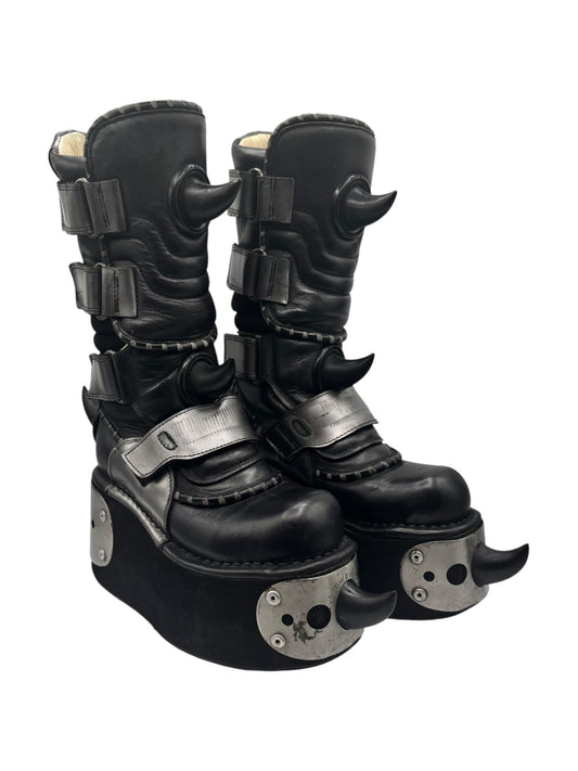 Black leather platform boots with chunky horn-like ankle details and silver strap buckles