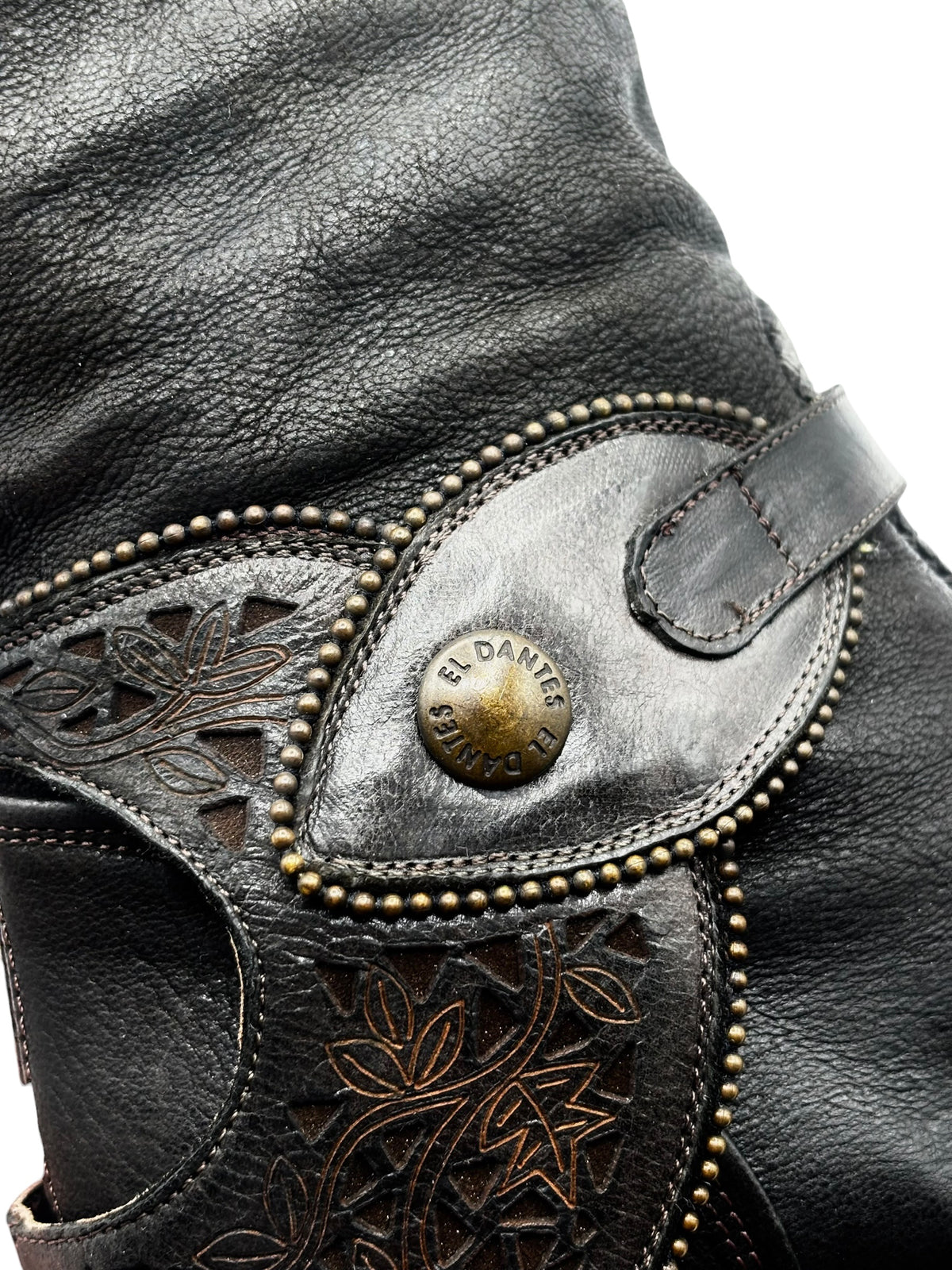 El Dantes knee-high black leather boot with decorative strap and brass logo button