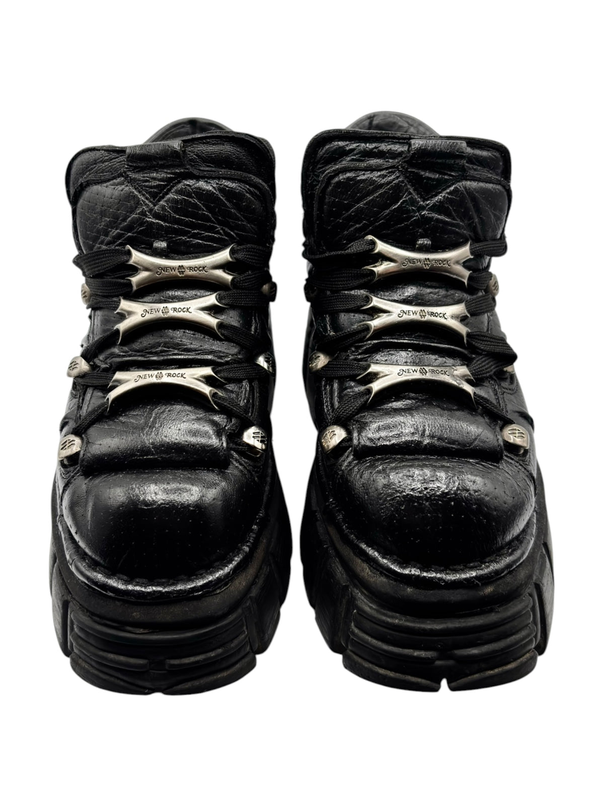 Back view of black platform boots with metallic logo detailing on heel