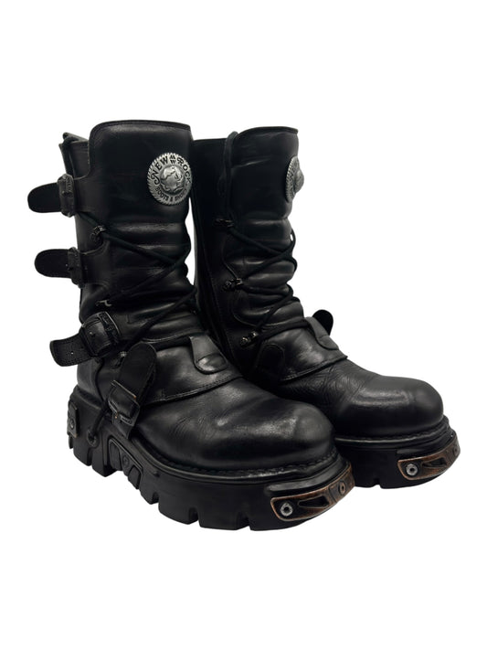 Black mid-calf leather boots angled side-back with lace-up ties and lug sole hardware.