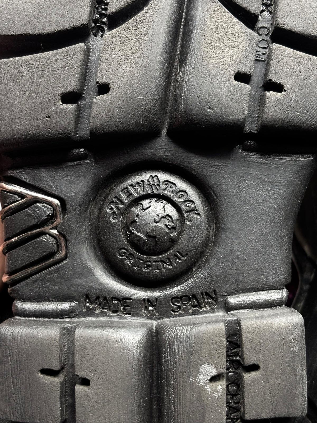 Black platform boot outsole with tread lugs and circular logo on heel