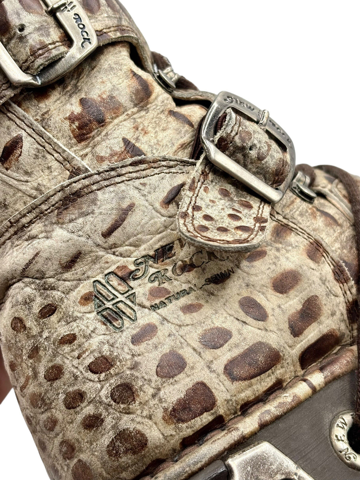 Desert-camo leather boot close-up with engraved buckle accents and textured lace details