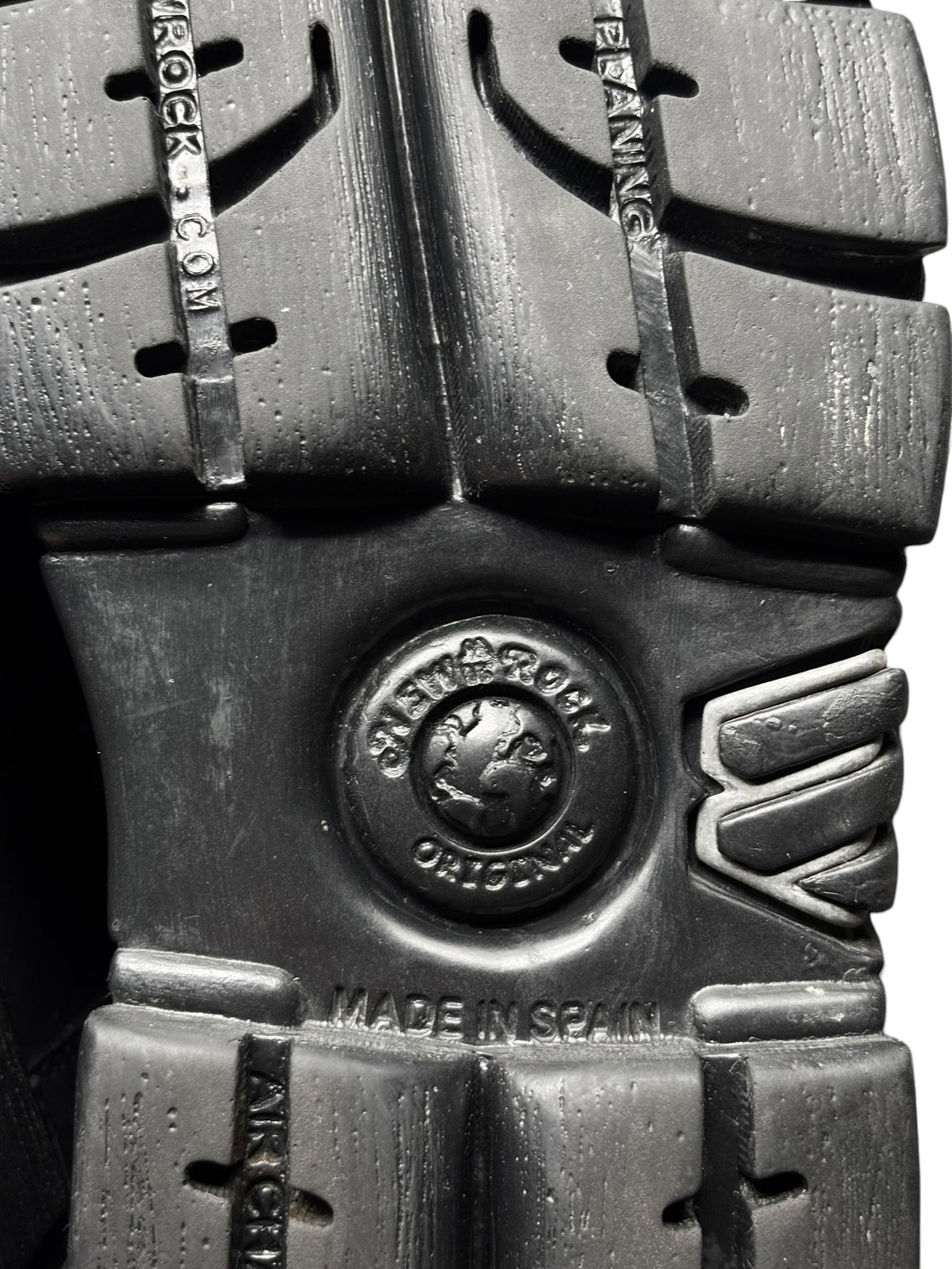 Black platform boot outsole with tread pattern and circular logo badge.