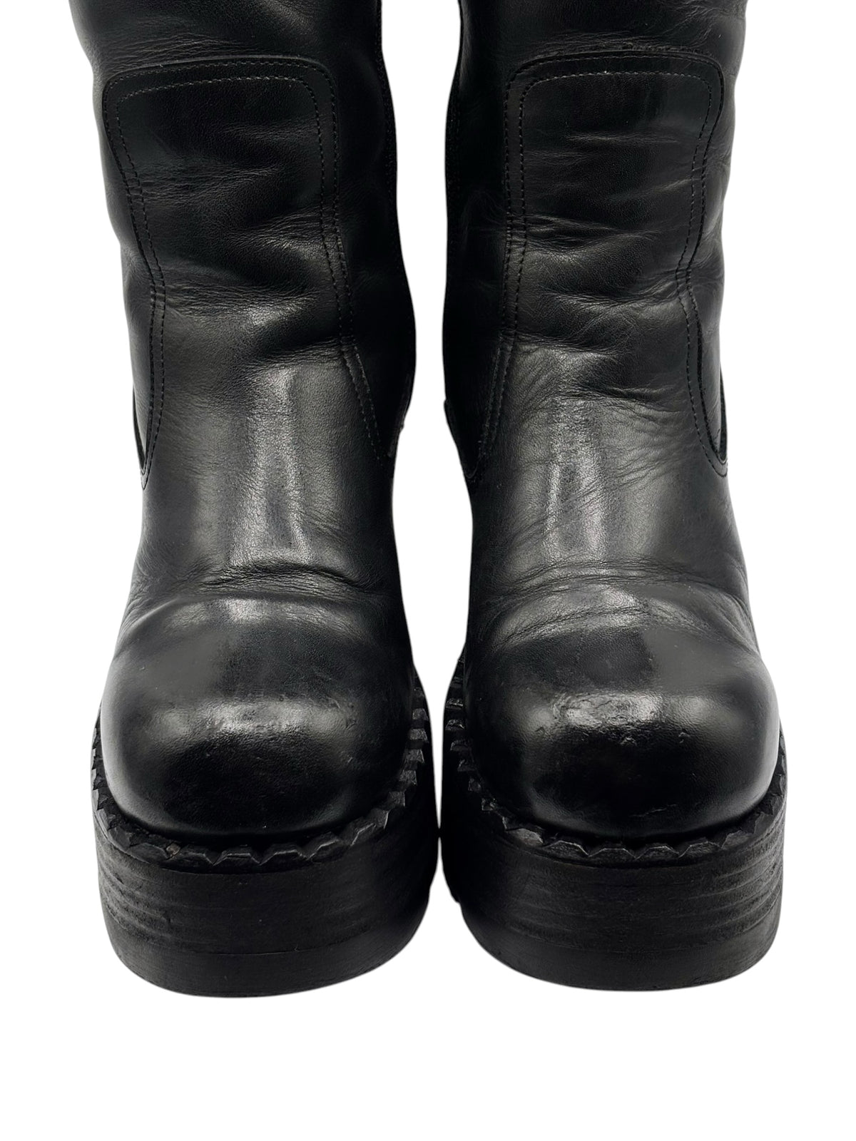 Black leather boot heels and toes with scuffed finish and thick rubber soles