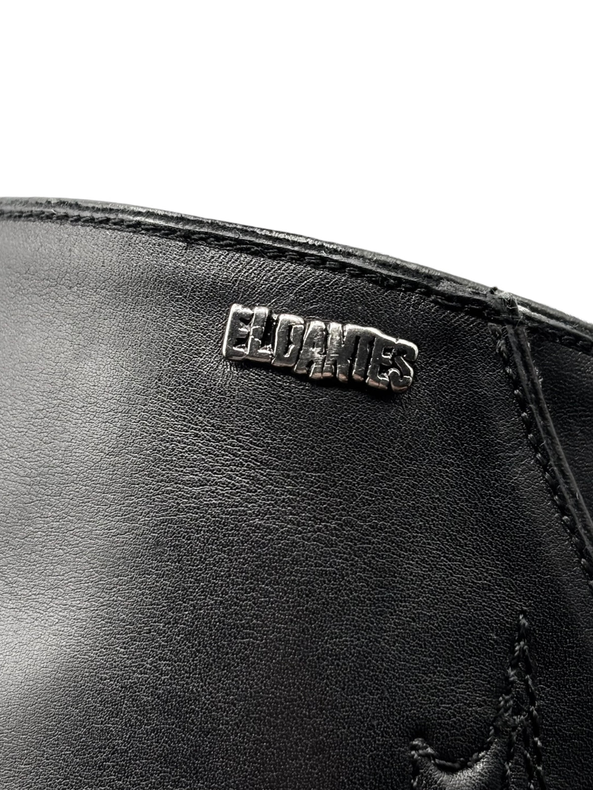Close-up of black leather boot logo patch reading EL DANTES
