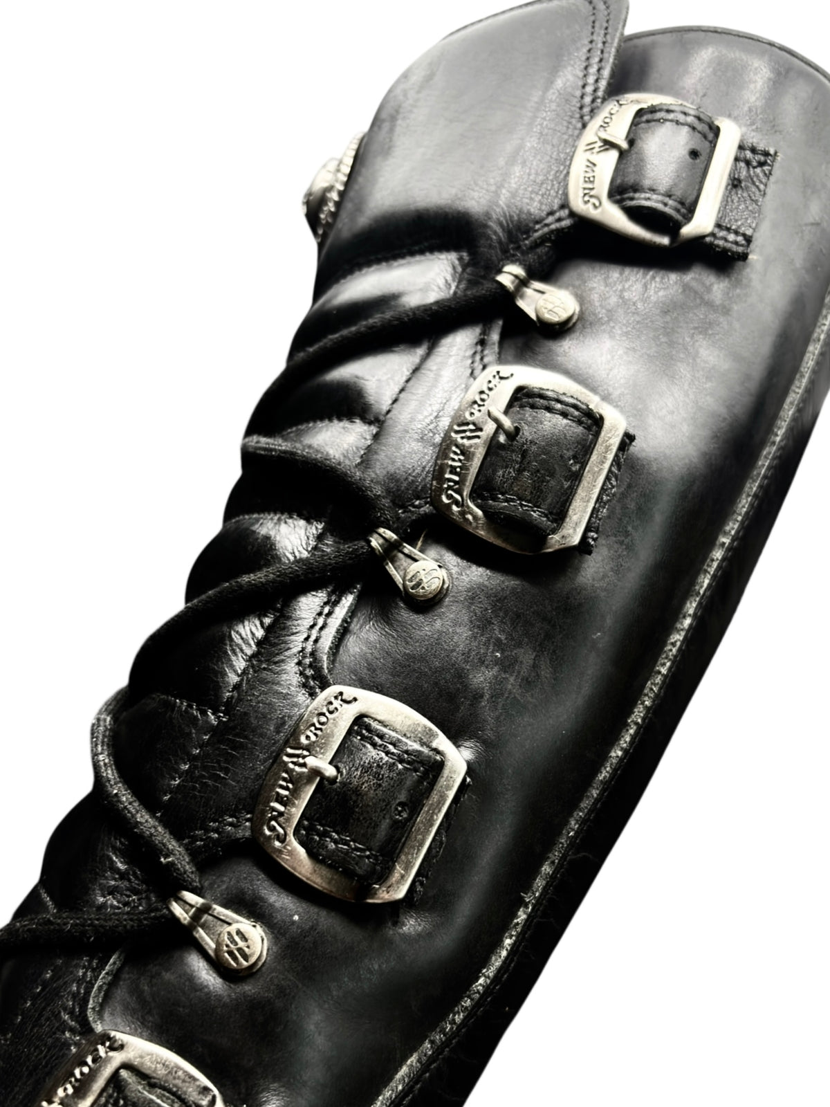 Black leather knee-high boots with embossed strap buckles and laced side panels