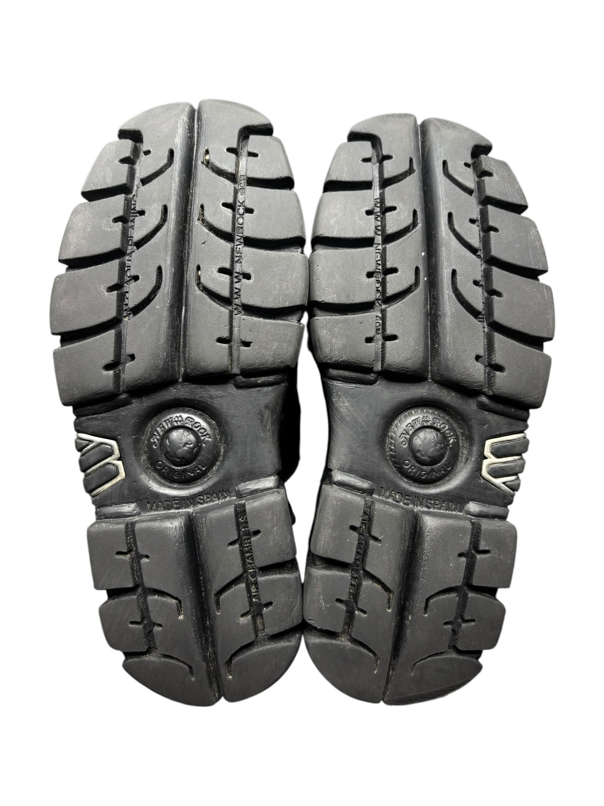 Pair of black platform boot soles with chunky tread and round emblem caps.