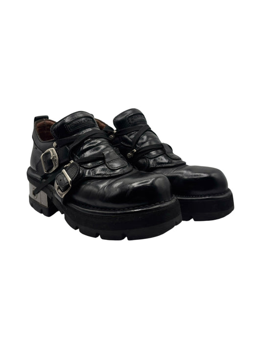 Black leather buckled raised-heel boots, angled side view with metal buckles