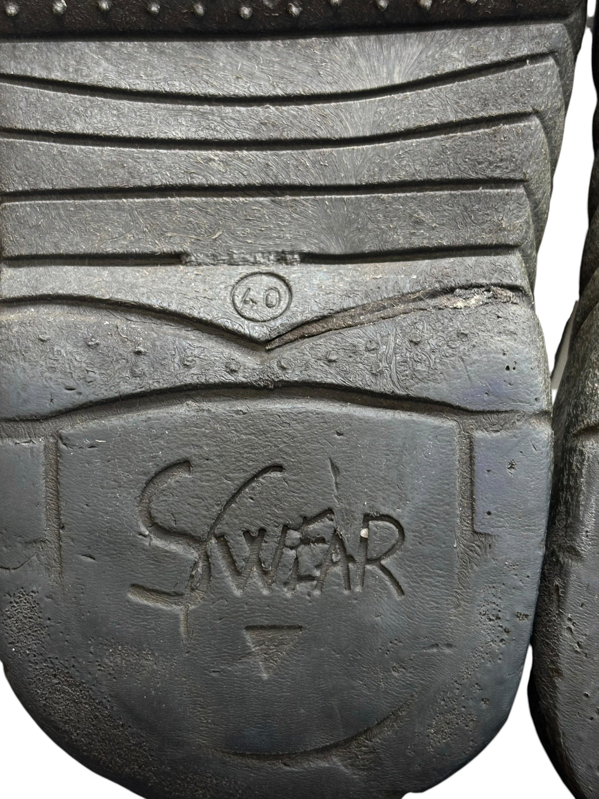 Swear logo on dark rubber boot outsole with textured tread and chevron grooves
