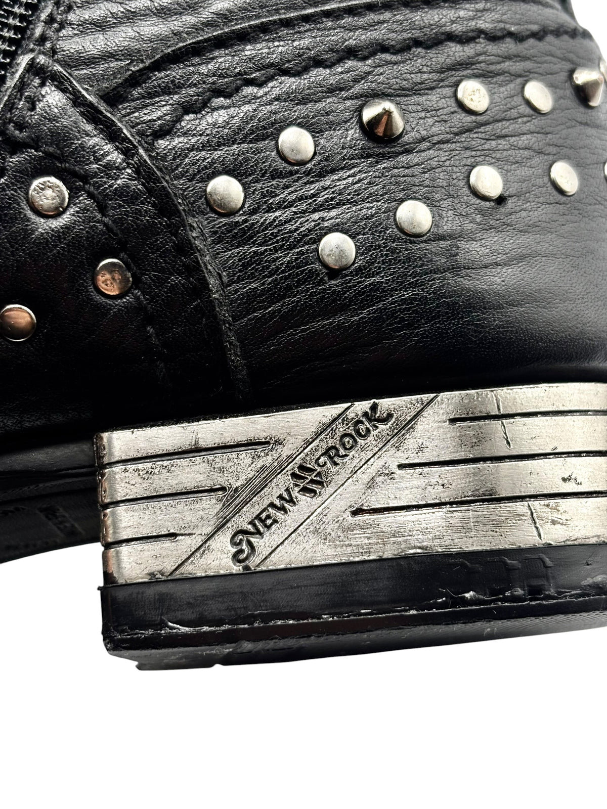 Close-up of black boot heel with metal studs and branded side plate detail.