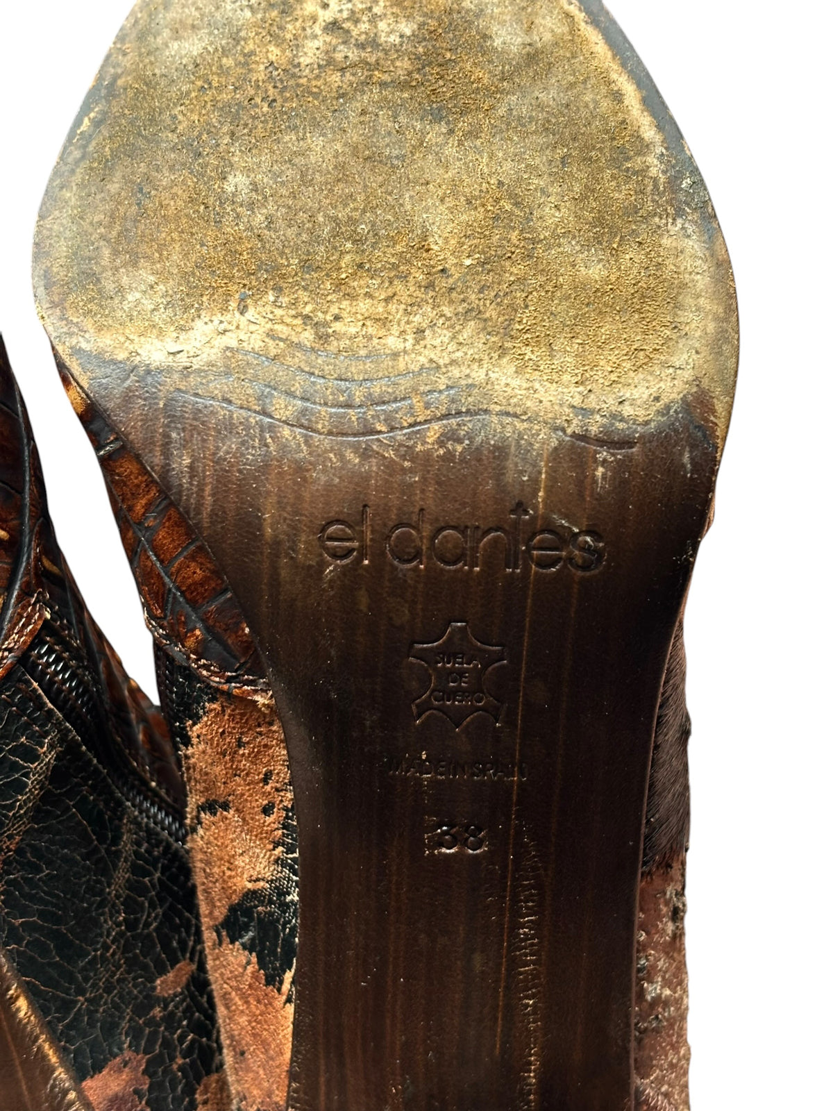 Boot footbed close-up with embossed “El Dantes” logo on worn brown leather.