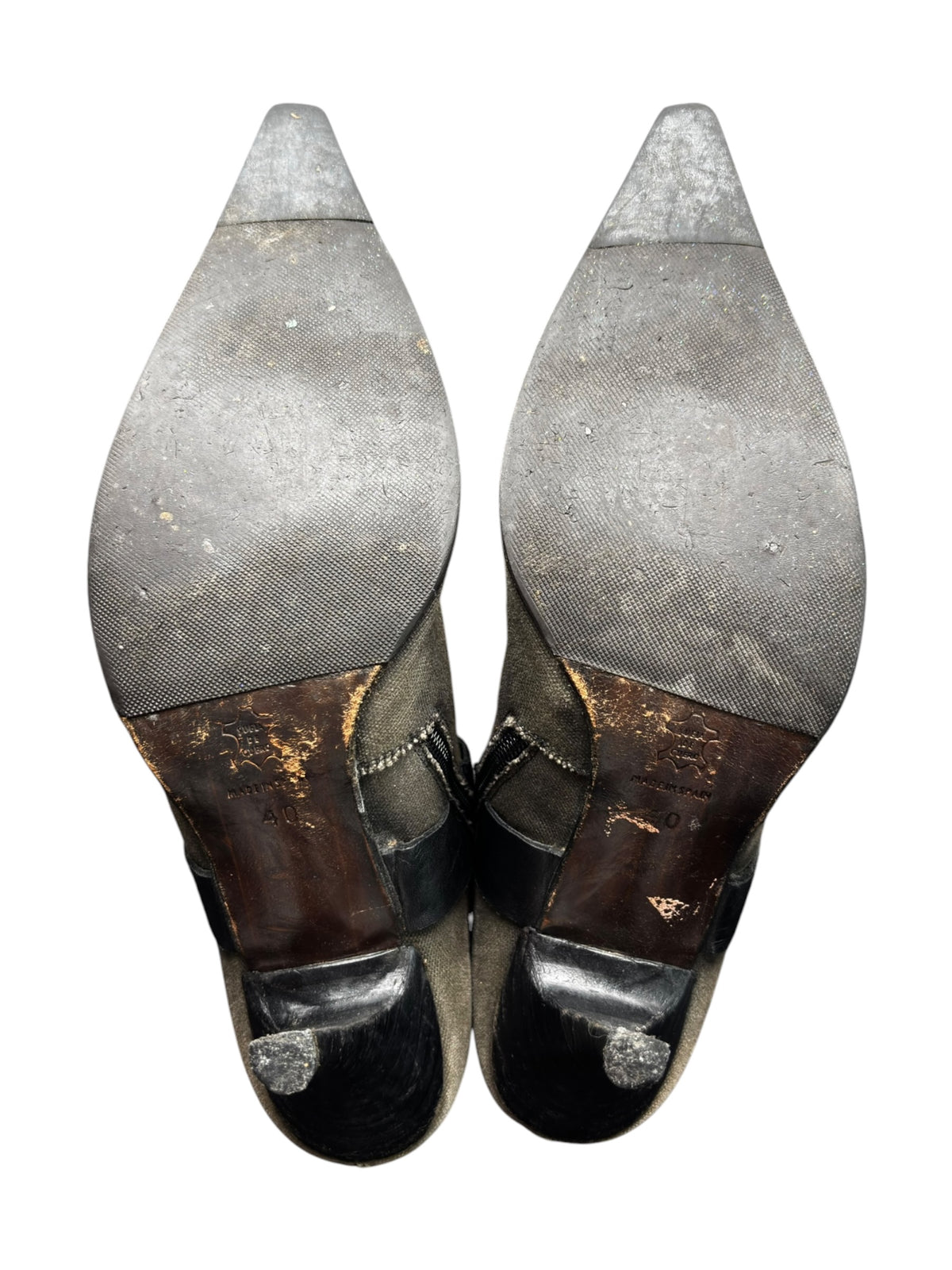 Pair of knee-high boots with pointed toe, worn patches, and dark rubberized caps