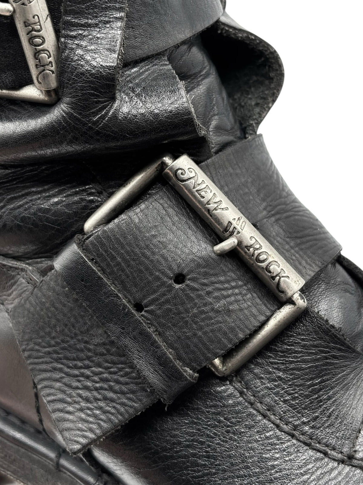 Black leather boot upper detail with engraved buckle and textured finish