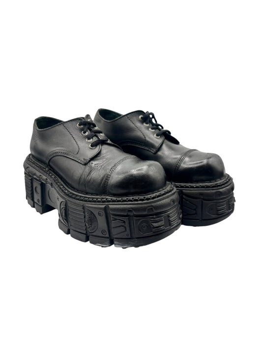Two black lace-up leather platform shoes, angled view showing thick tread soles