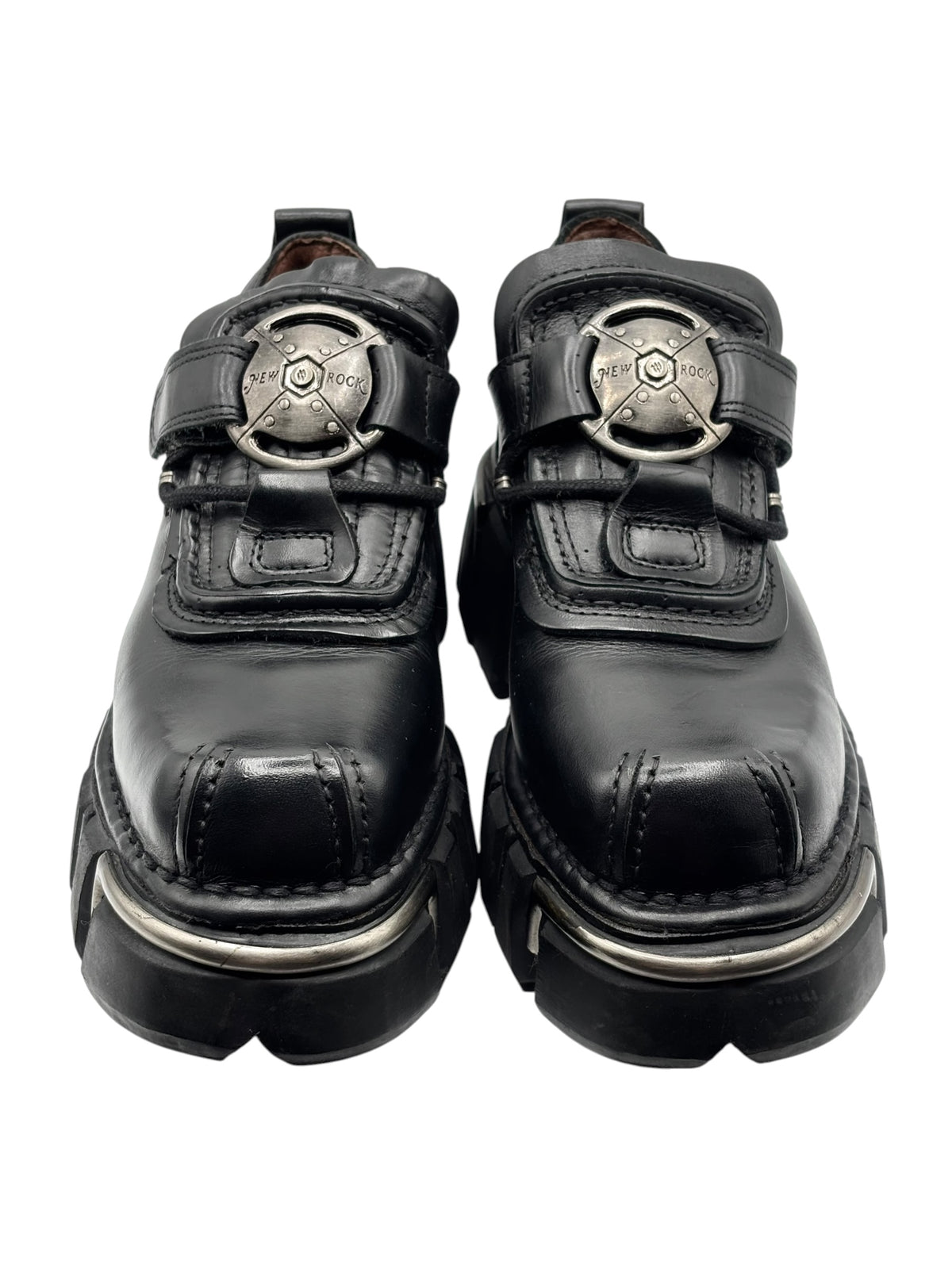 Vintage black platform boots with buckled straps and metal emblem, front view