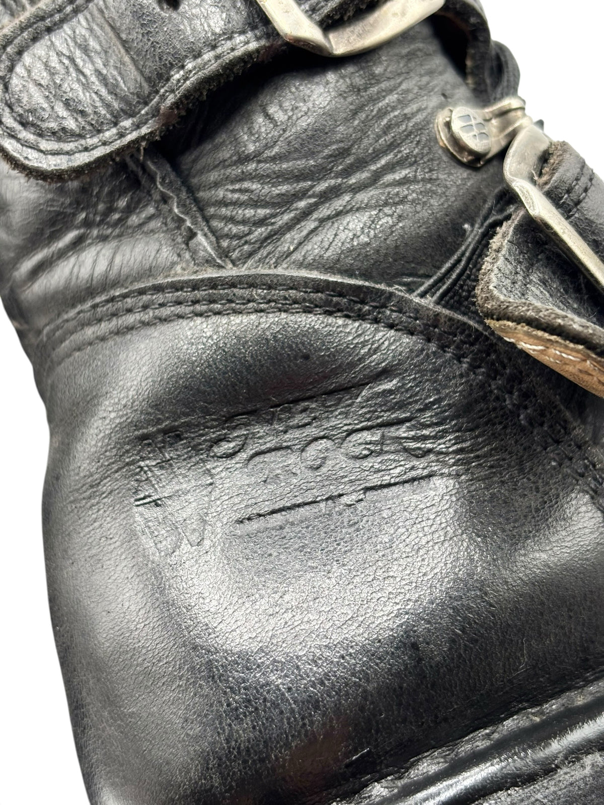 Black leather boot upper with stitched seam and embossed logo patch