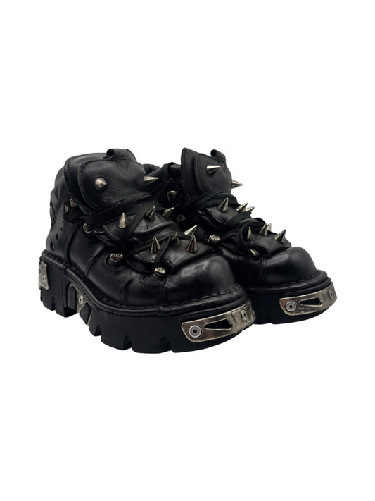Black spiked platform boots, side view with chunky outsole and silver strap hardware