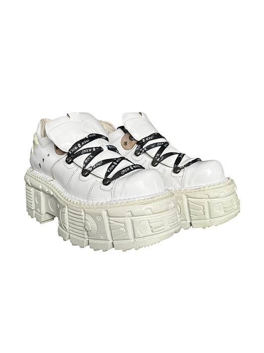 White leather platform boots with black lace-up straps and chunky textured sole