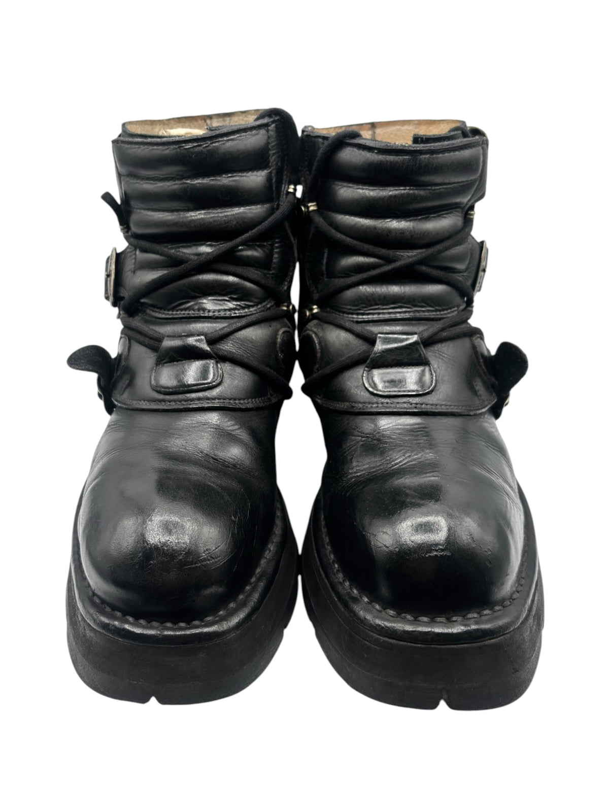 Front view of black raised heel ankle boots with gathered straps and metal buckles