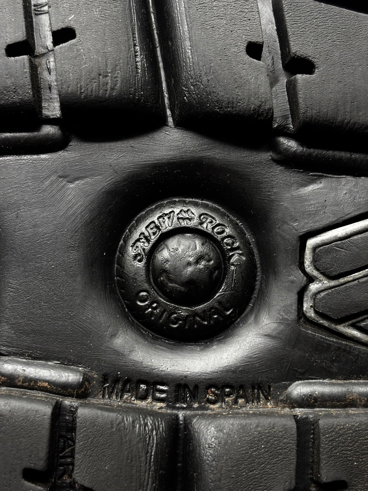 Black boot outsole detail with round logo badge and “Made in Spain” mark