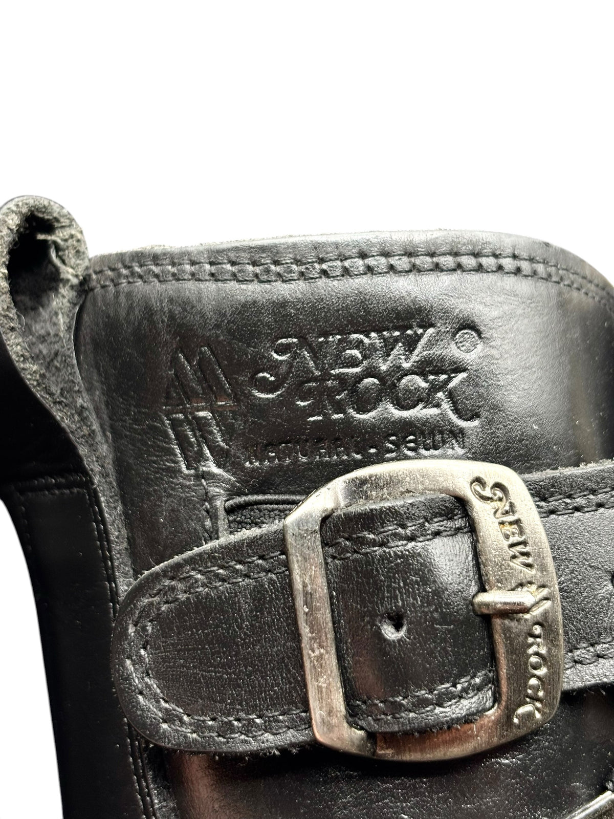 Close-up of black boot interior with “NEW ROCK” branding and metal buckle detail.