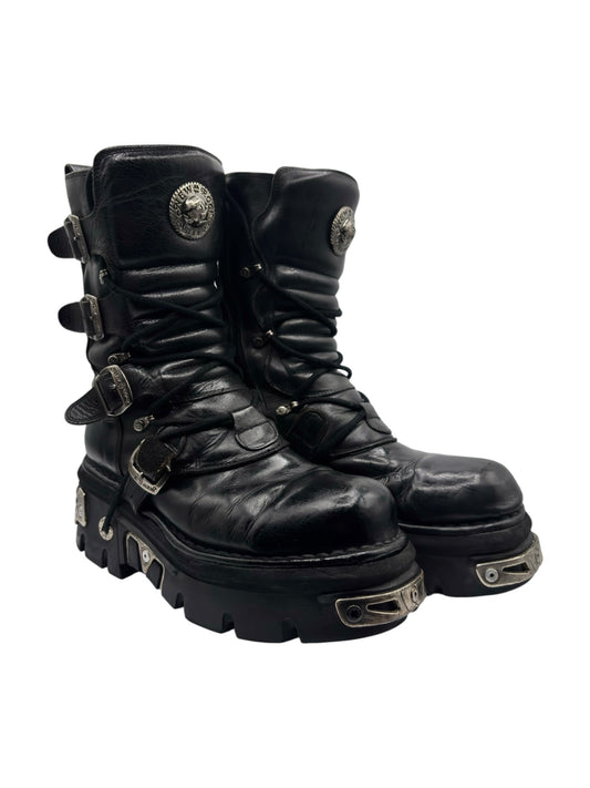 Mid-calf reactor boots, black leather lace-up with side emblems, chunky tread sole and straps