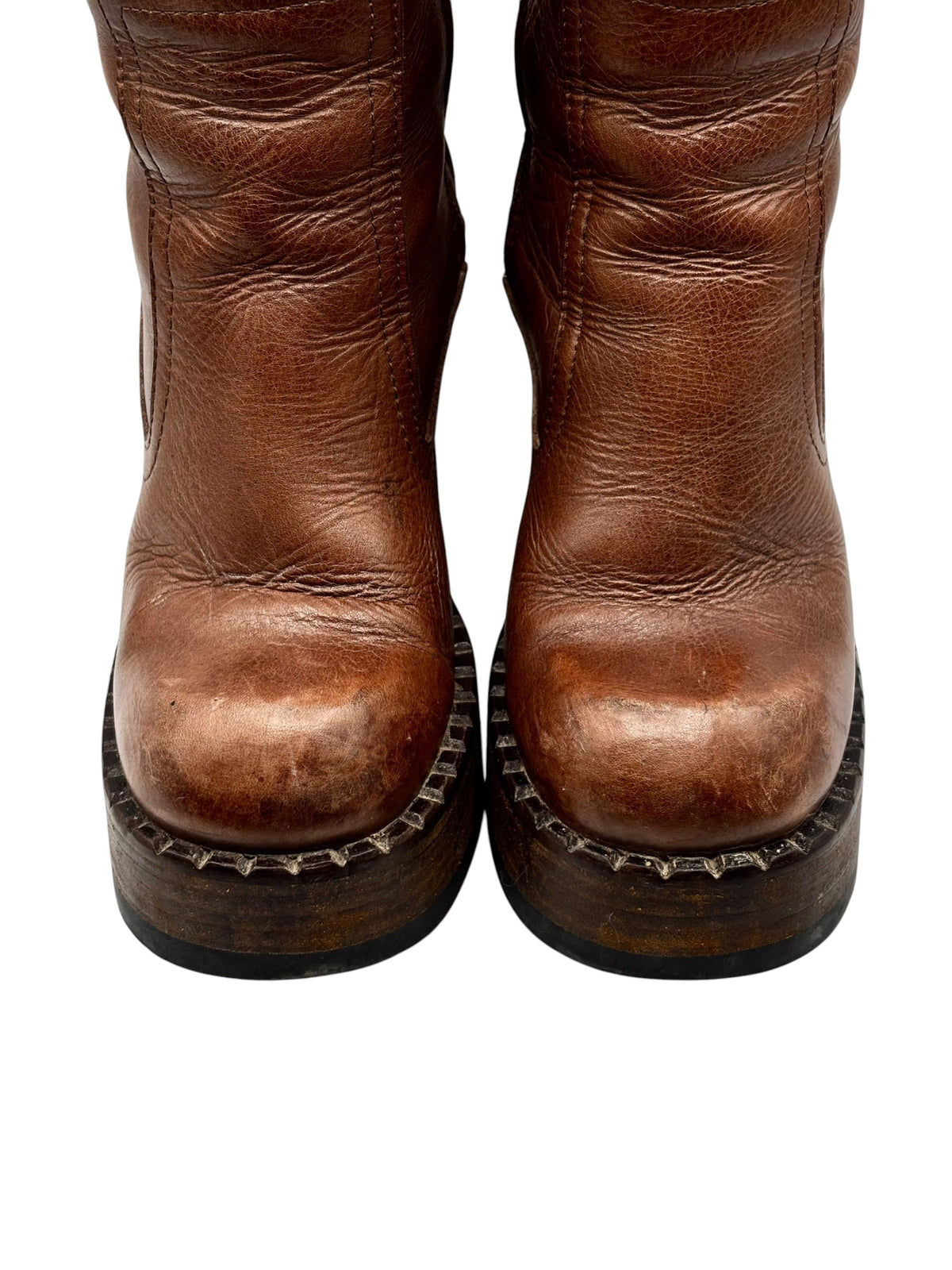 Brown knee-high boots with distressed toes and dark platform soles.