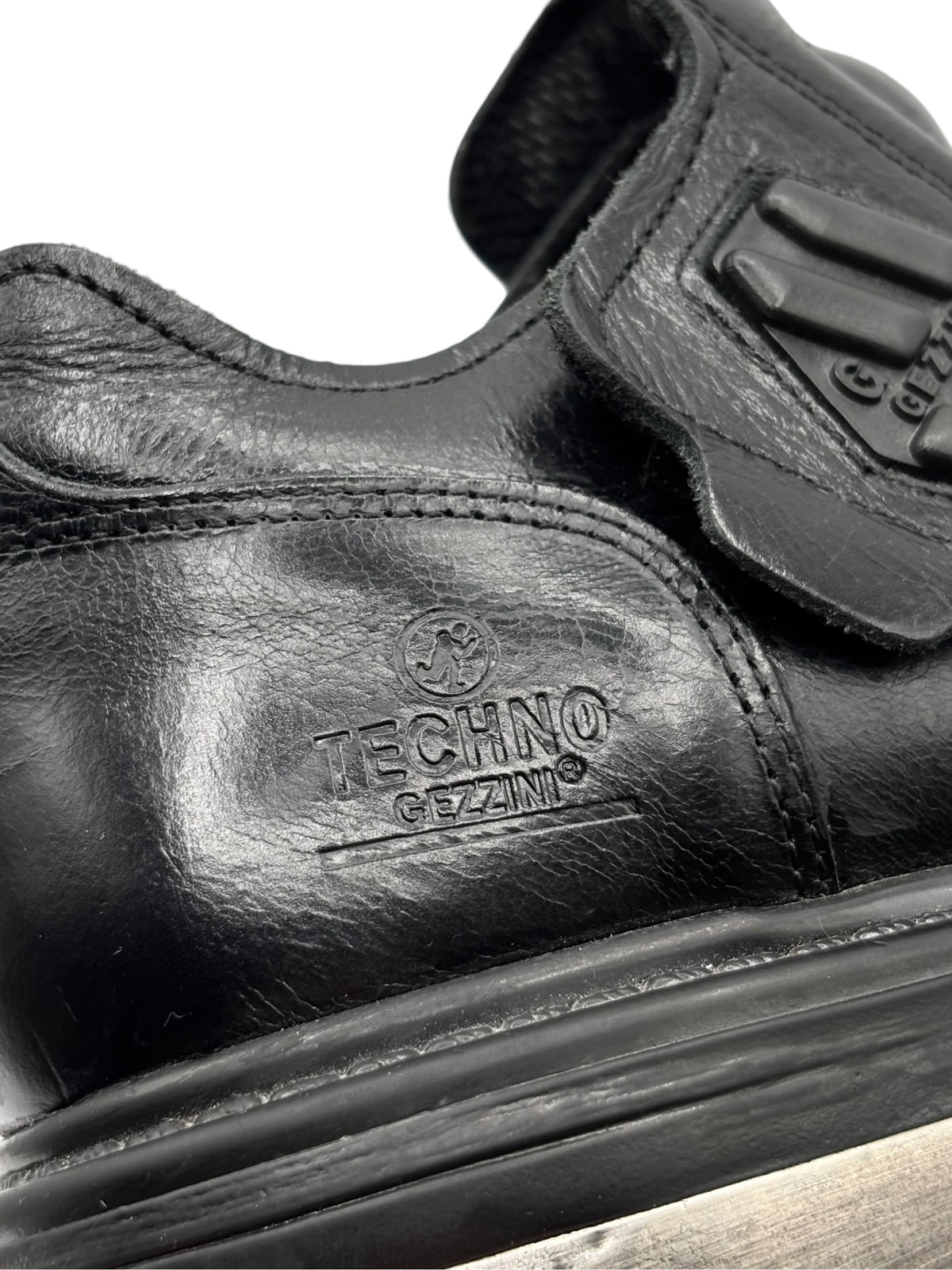 Close-up of black ankle boot with TECHNO GZANA logo and textured leather panel