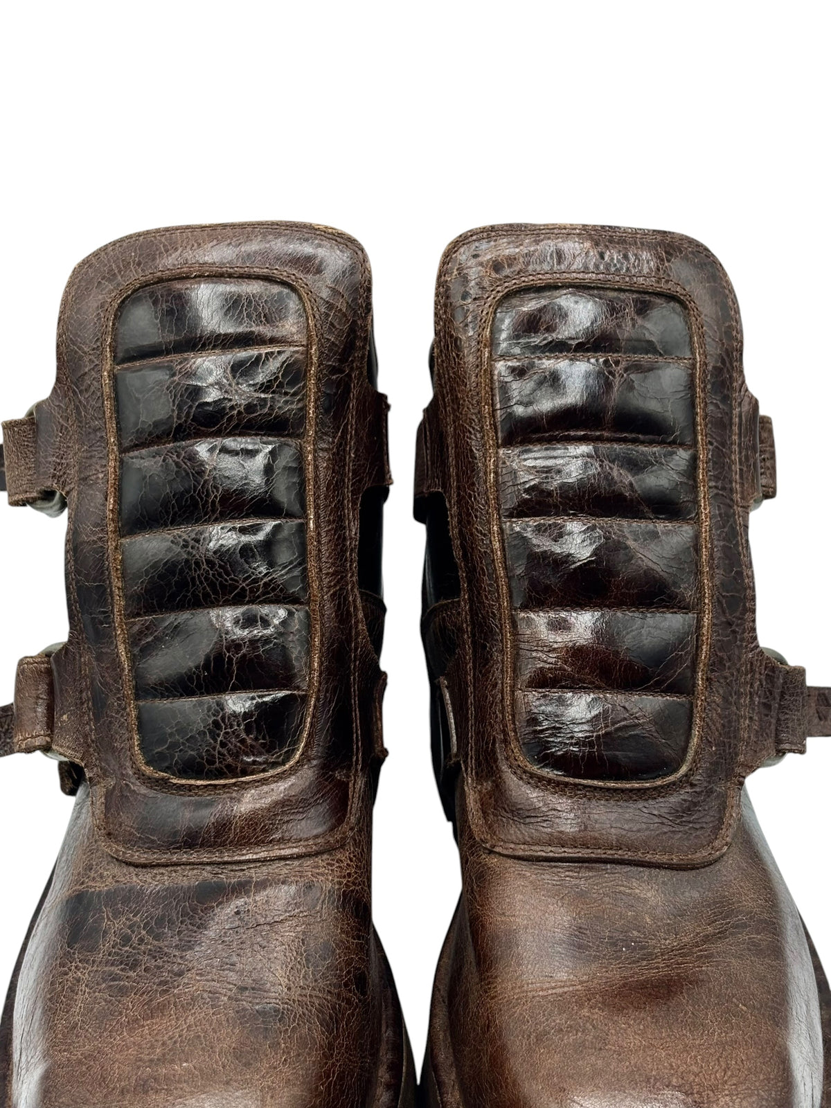 Close-up of brown leather boots with side straps and textured leather panels