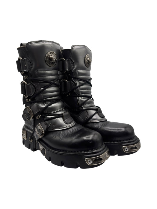 Black mid-calf leather boots with buckles, straps, and chunky rubber sole