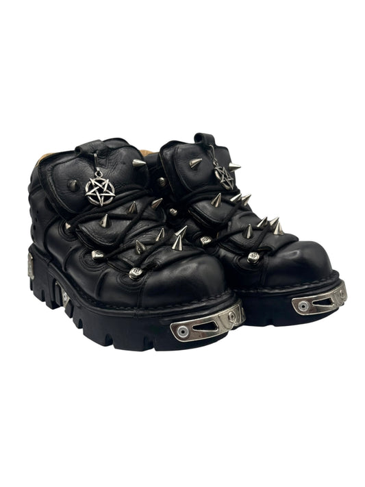 Angled view of black lace-up platform boots with spike studs and star charm