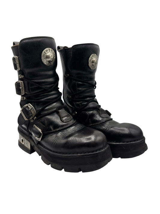 Black leather mid-calf boots with layered buckles, stitched seams, rugged sole
