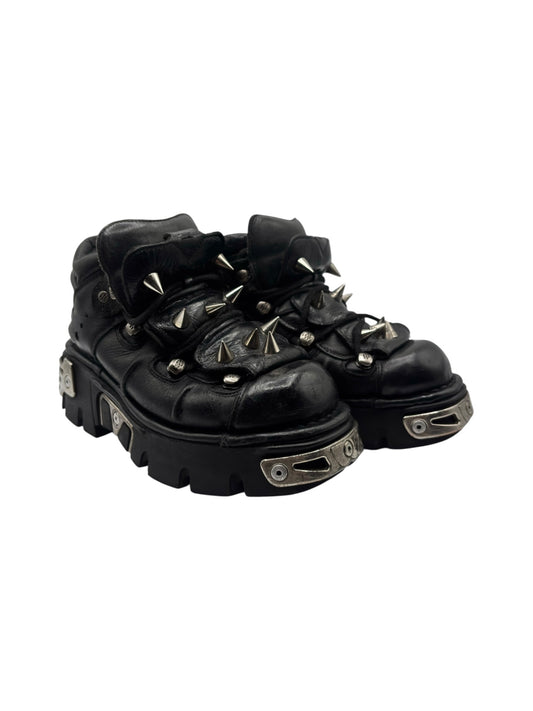 Black lace-up platform boots angled view with spiked collar trim and metal side straps.
