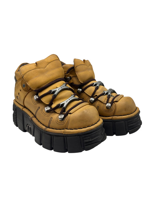 Angled view of mustard platform boots with black chunky sole and lace-up closure