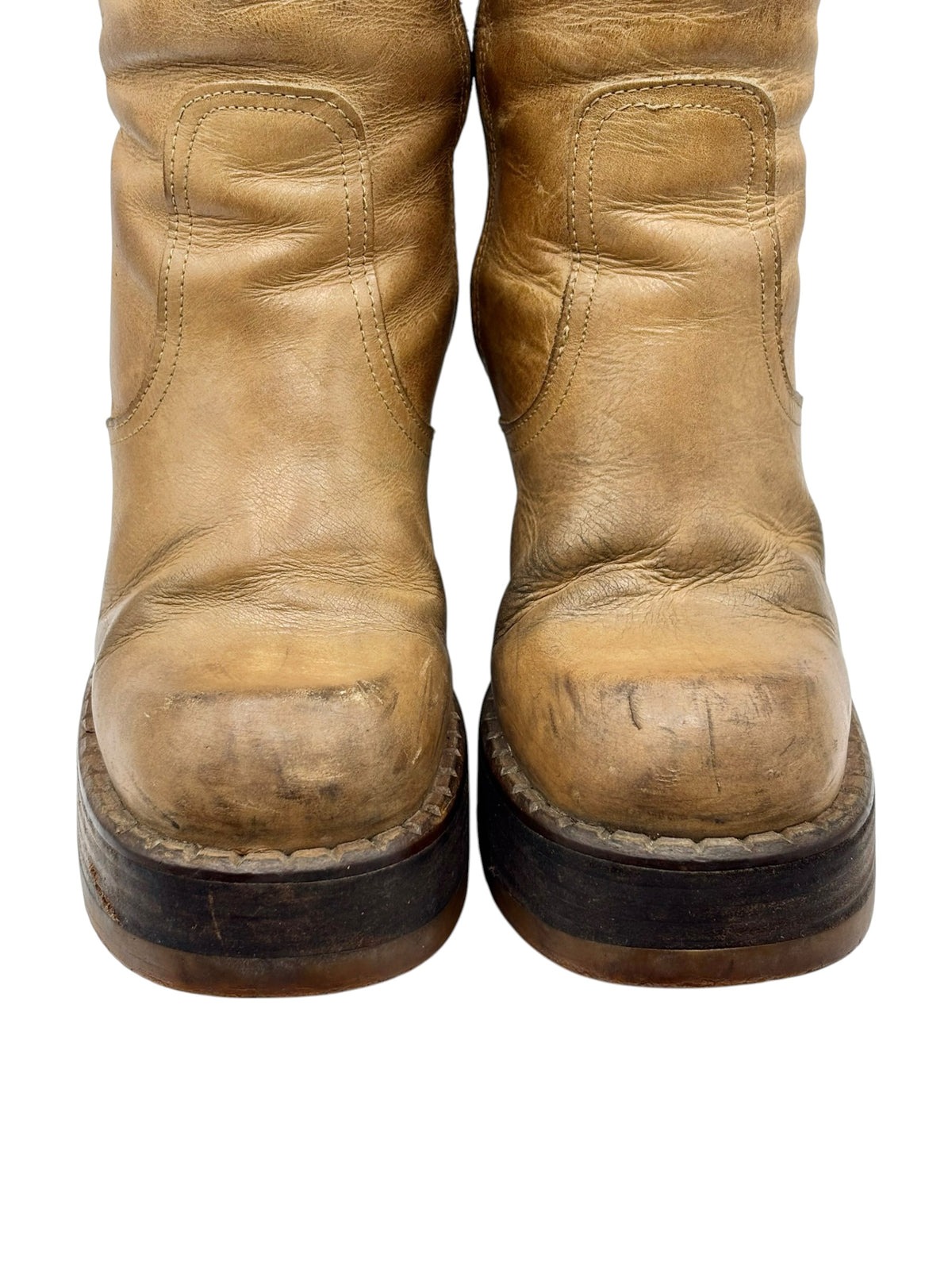 Close-up of tan boot uppers and rounded toes, showing creases and scuffed soles.