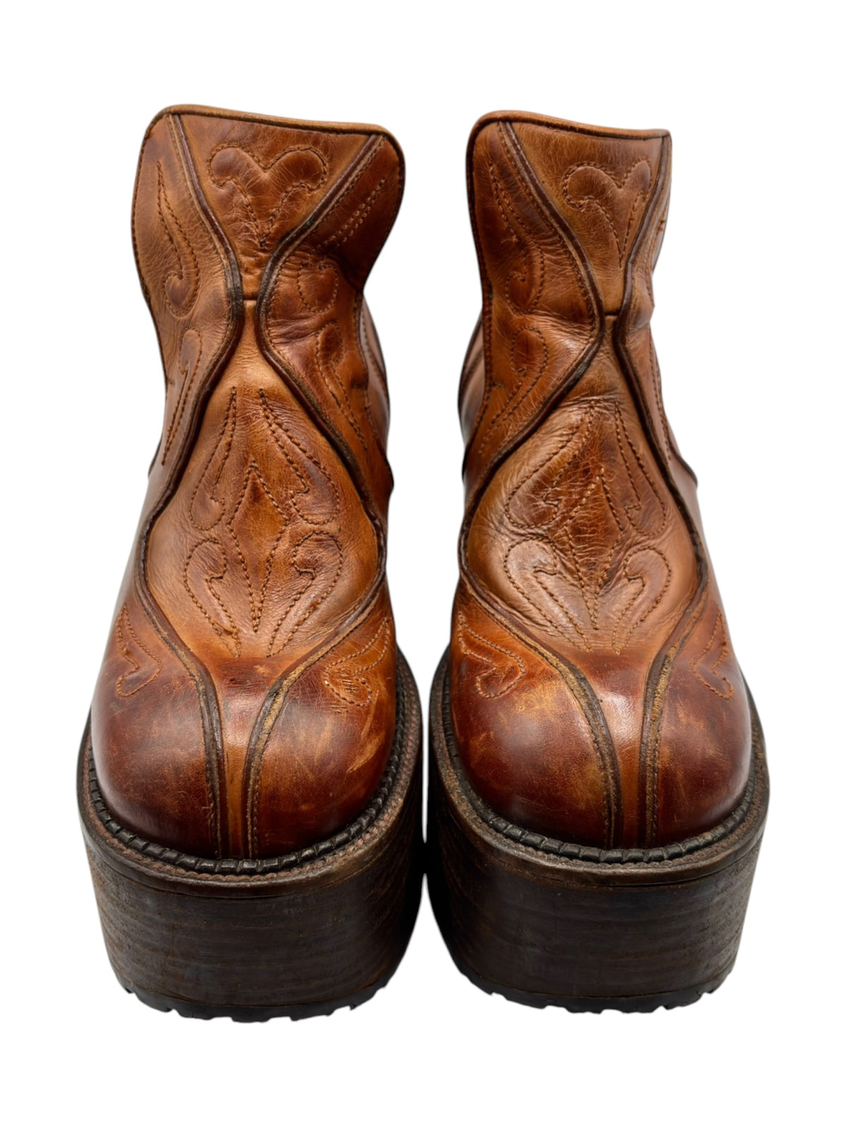 Brown leather platform ankle boots with ornate curved stitching and thick soles