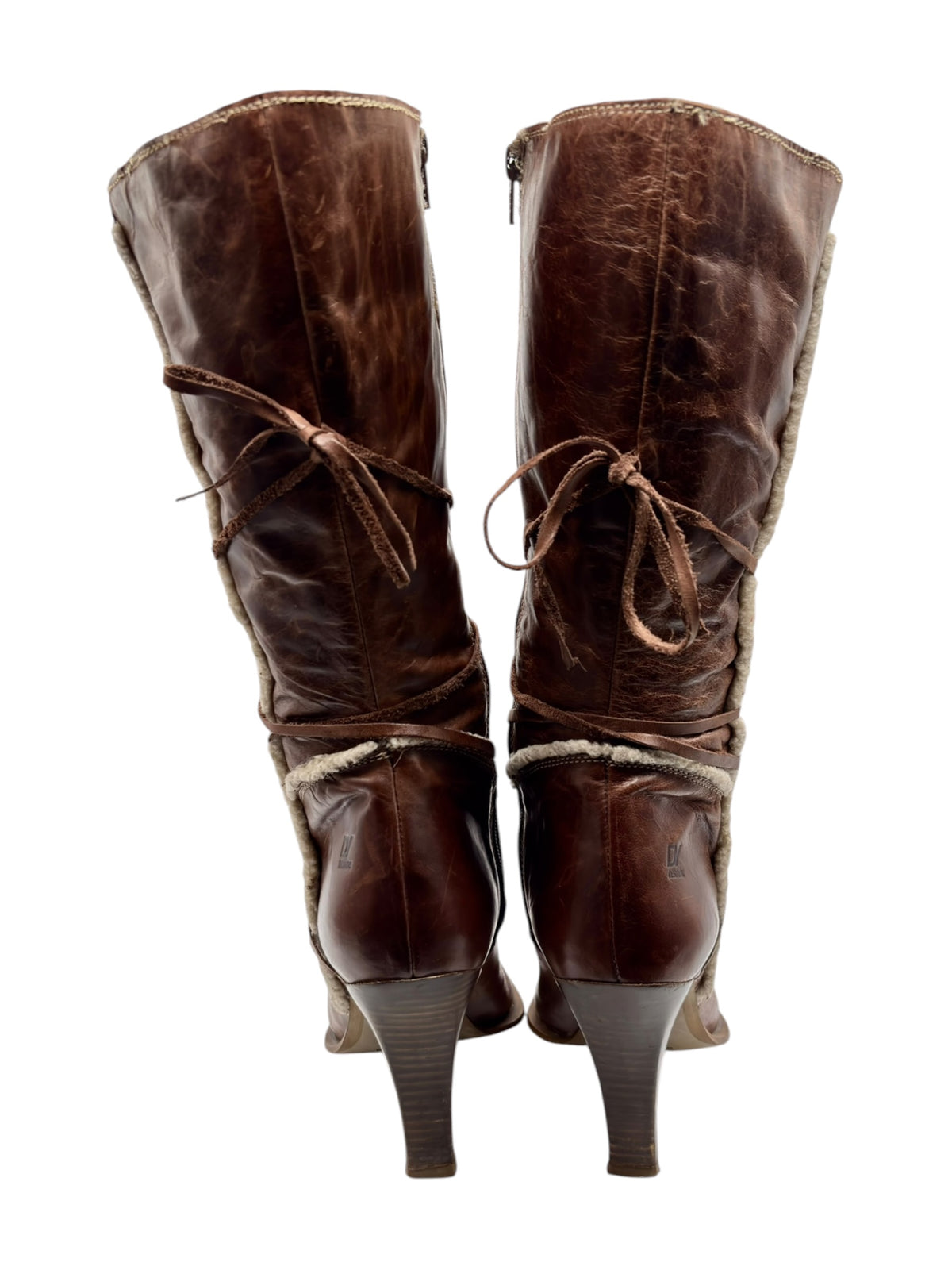 Brown pair of pointed boots with side laces, zip closure, and shearling trim.