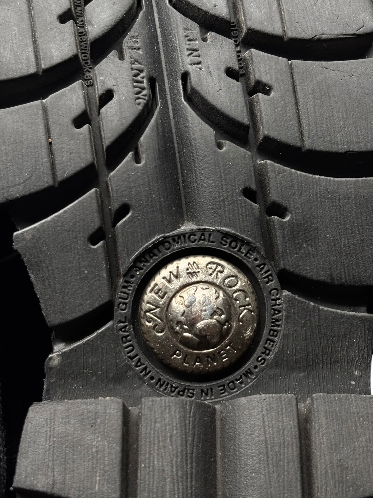 Vintage New Rock pluto platform boots: rubber tread and circular logo plate close-up
