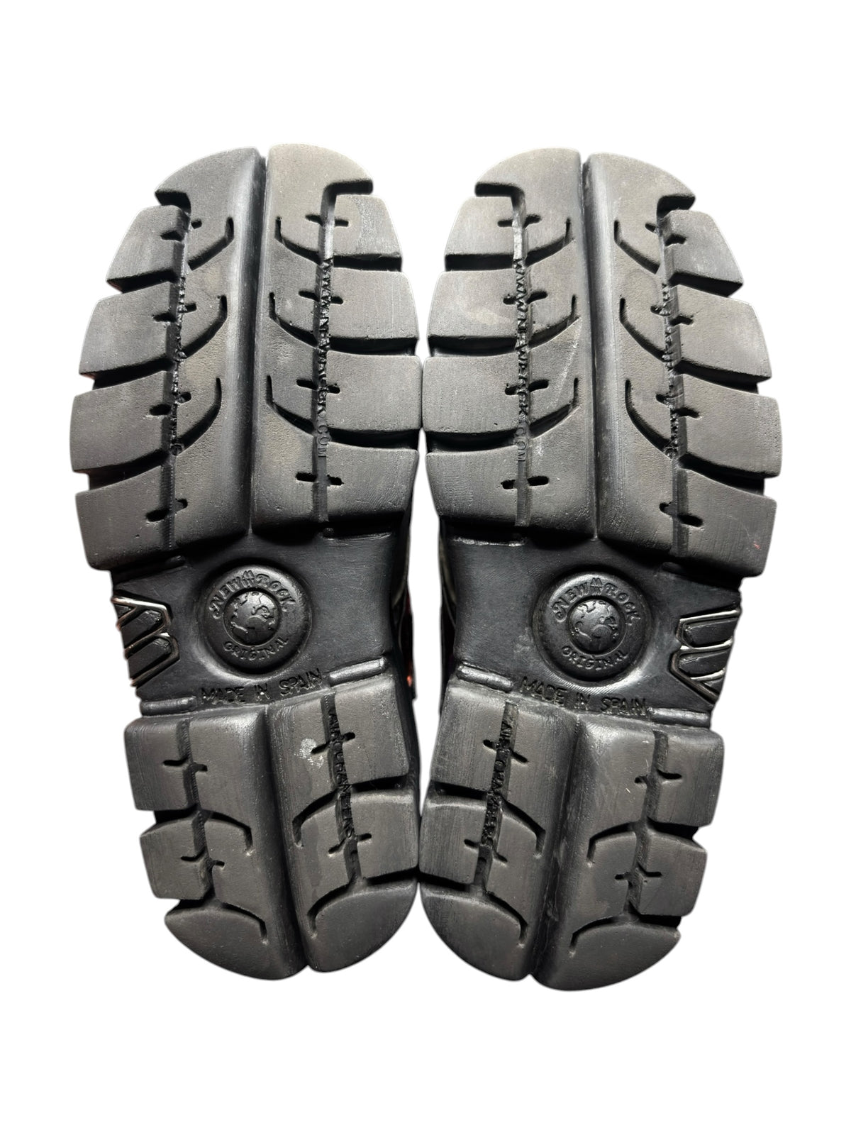 Pair of black lug soles with circular heel branding and deep tread pattern