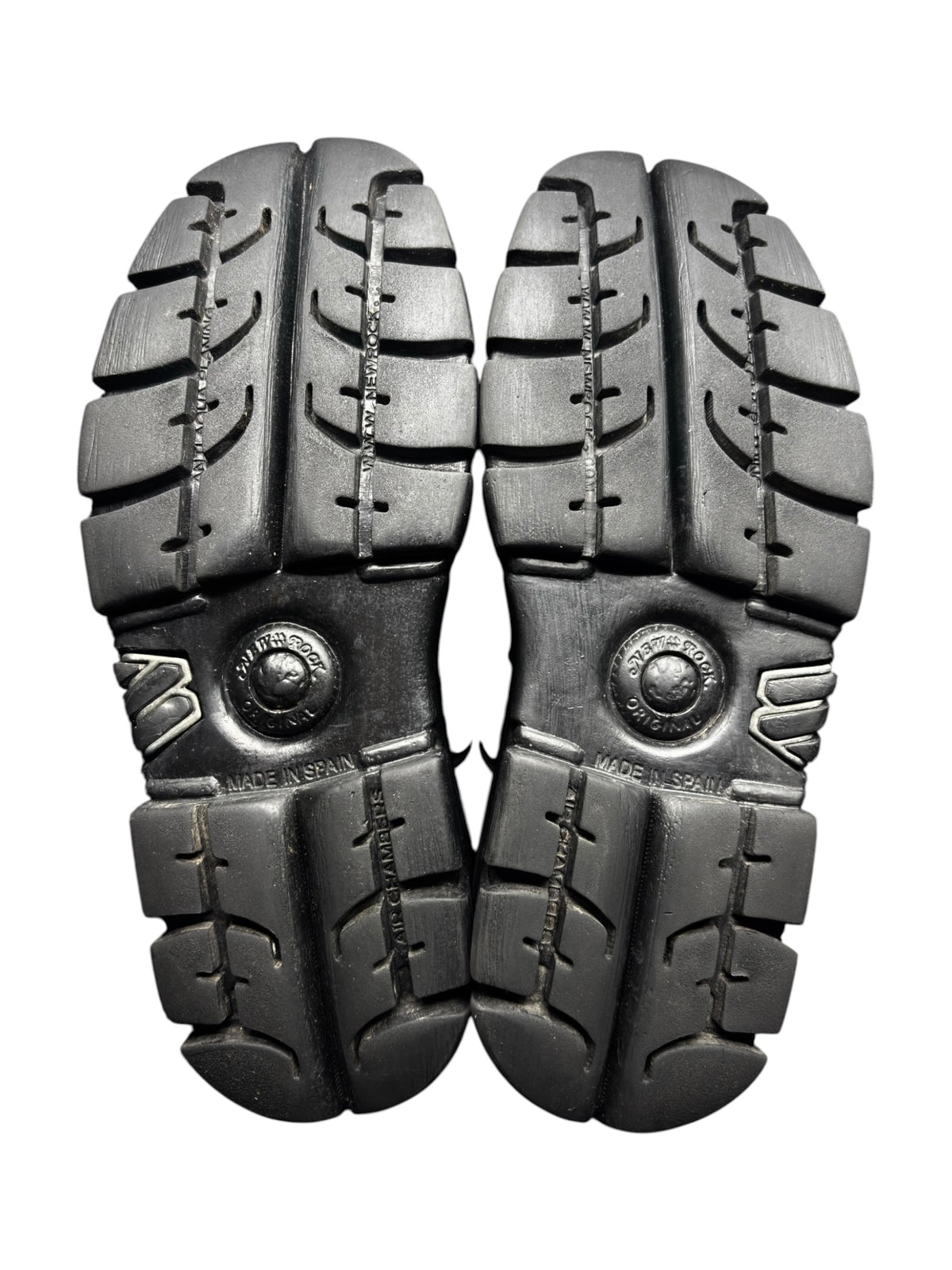 Black platform boot outsole view with chunky tread and metal circular logo near heel